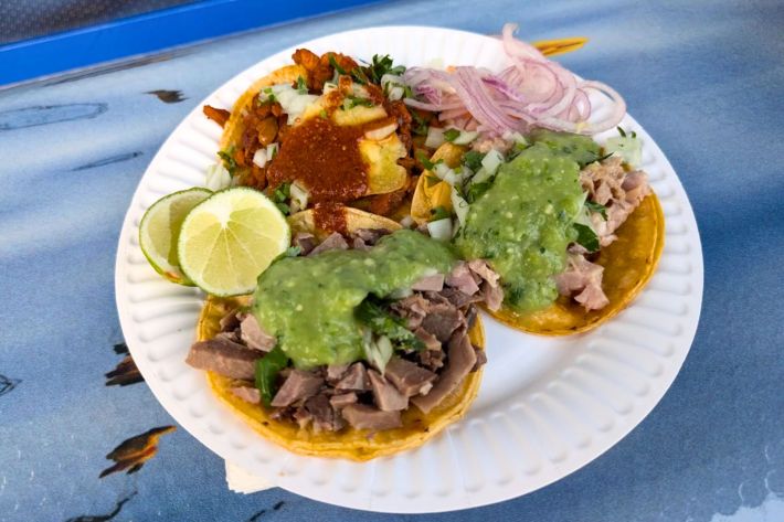 taco de al pastor, lengua and more on a paper plate.